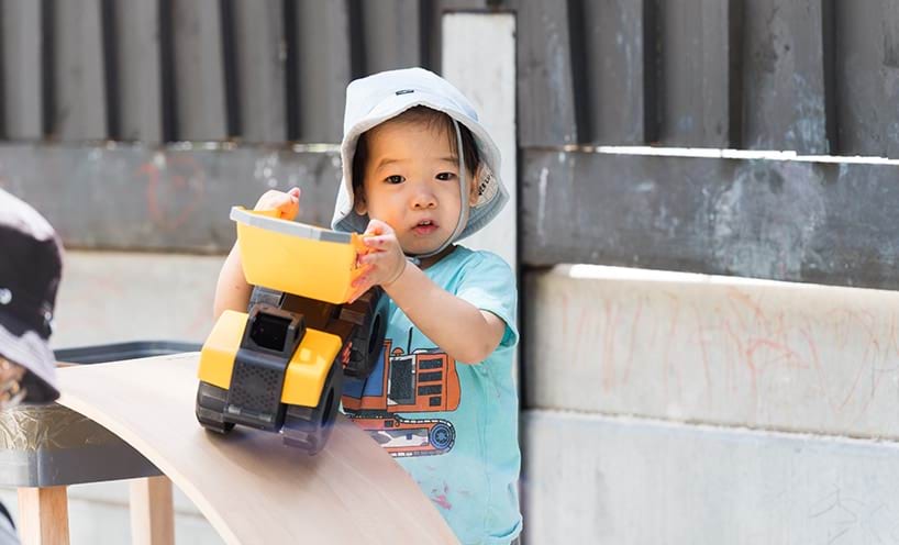 A young child playing with a plastic digger toy.