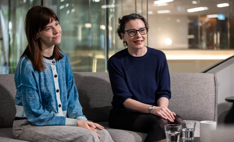 Two women sitting on a couch in an office,