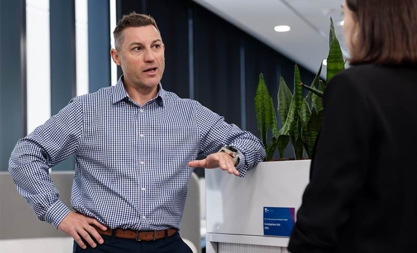 Man and women talking in an open plan office.