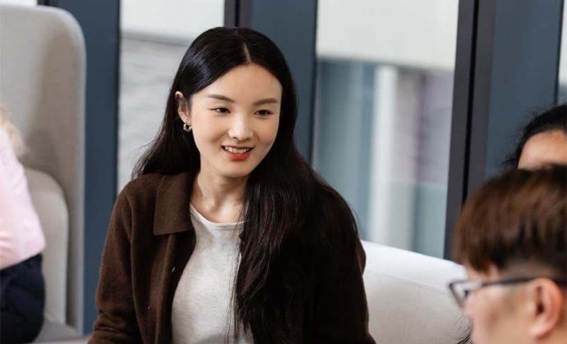 A professional woman in a work setting smiling at the camera.