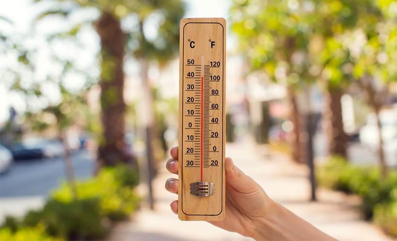 A hand holding up a barometer to measure the weather temperature 